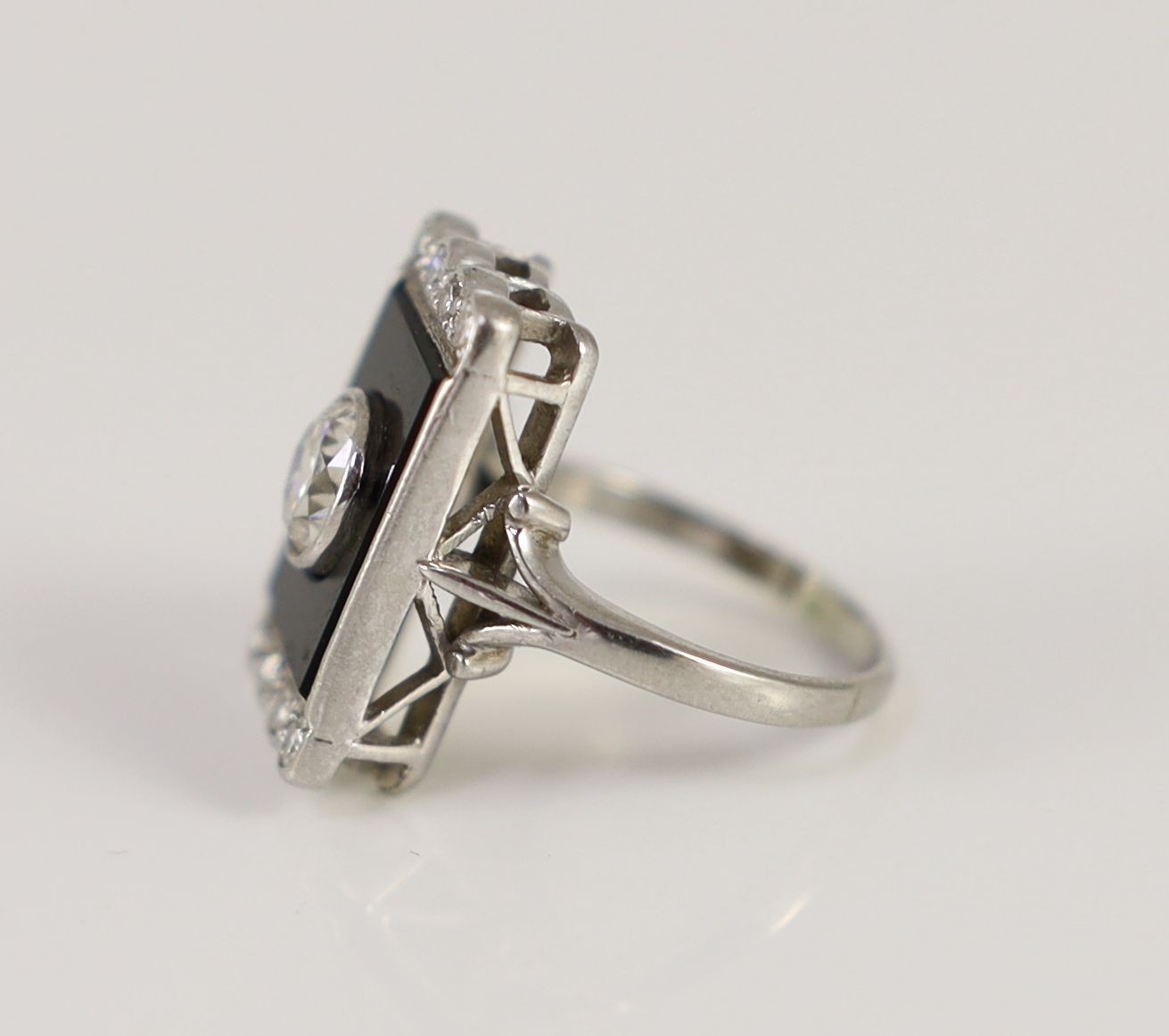 A platinum, single stone diamond and black onyx set rectangular tablet ring, with eight stone diamond setting